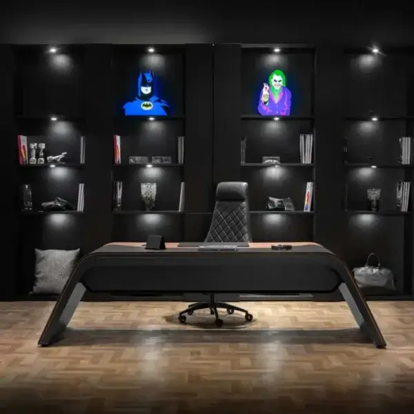 Rectangular desk with black glossy surface, light wood angular base, silver handle, and bat figurine, paired with black leather executive chair.
