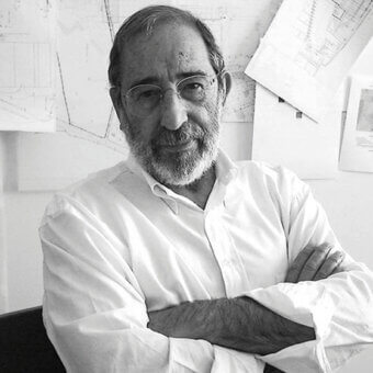 Architect Álvaro Siza portrait, black and white, seated with crossed arms, wearing glasses, with architectural drawings in background.