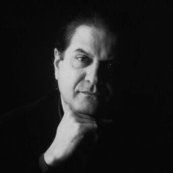 Black and white portrait of Mario Barbaglia, three-quarter view, dark hair, black collared shirt, hand resting on chin, dramatic lighting.