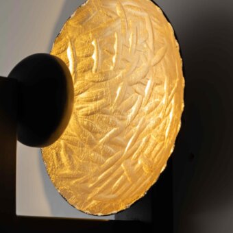 Elegant Stillux Random wall lamp with a curved textured gold hammered metal shade and rigid black metal support