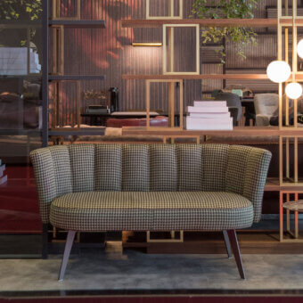 Distinguished Borzalino Diva sofa with shell form upholstered in dark houndstooth textile and lacquered metal base