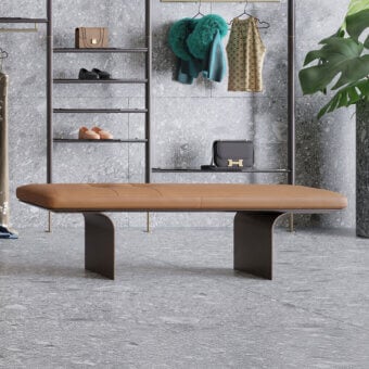 Borzalino Minerva bench, tan leather, curved gray supports with brass legs, modern gray interior with shelving and clothing rack.
