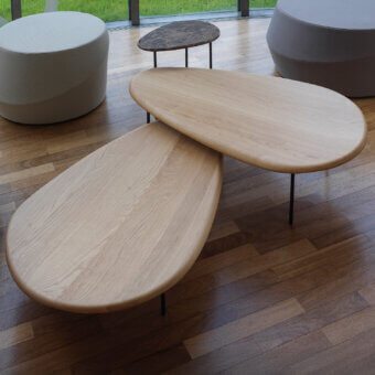 Exceptional Casamania Lily coffee table presents overlapping light-toned wooden tops with smooth grain supported by dark painted metal legs