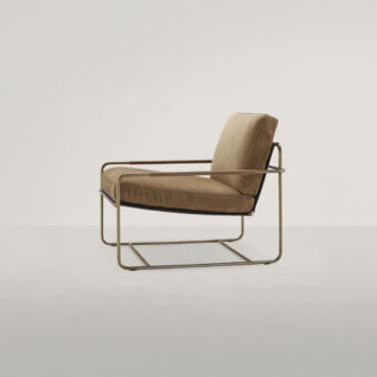 Riviera lounge chair, tan textured leather, brushed brass metal frame, rectangular silhouette, minimalist design, low profile seating.