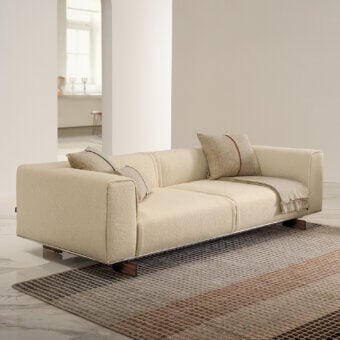Distinguished Horm Coleman sofa with light beige textile and solid canaletto walnut feet, showcasing two red-lined cushions
