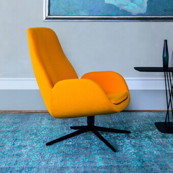 Captivating Bross Mysa lounge chair with vibrant yellow-orange fabric upholstery and lacquered metal base