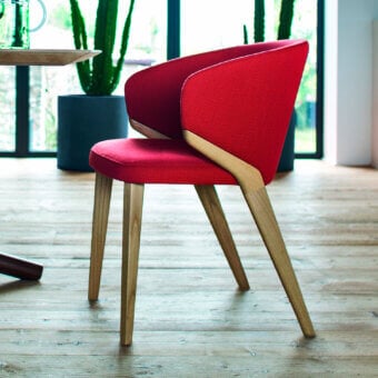 Handcrafted Bross Nora armchair with red fabric upholstery and a light-toned wood frame exhibiting curved lines and a smooth finish