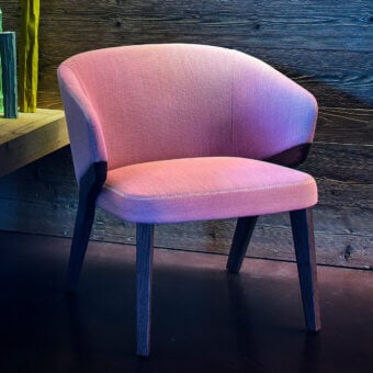 Exceptional Bross Nora lounge chair with rounded silhouette fully upholstered in pink fabric and dark-toned wood structure
