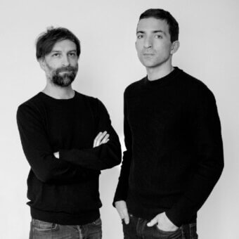 Black and white studio portrait of two men in black sweaters and jeans, with names “alberto saggia & valerio sommella” below.