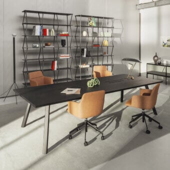 Lapalma workstation with stained wood tabletop, A-frame brushed metal base, and four tan upholstered chairs, plus gray shelving unit.