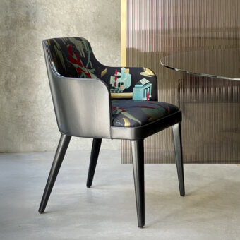 Lola Royale chair by Casa Casati, dark patterned fabric, curved shell with flared seat, gray armrests, black metal tapered legs.