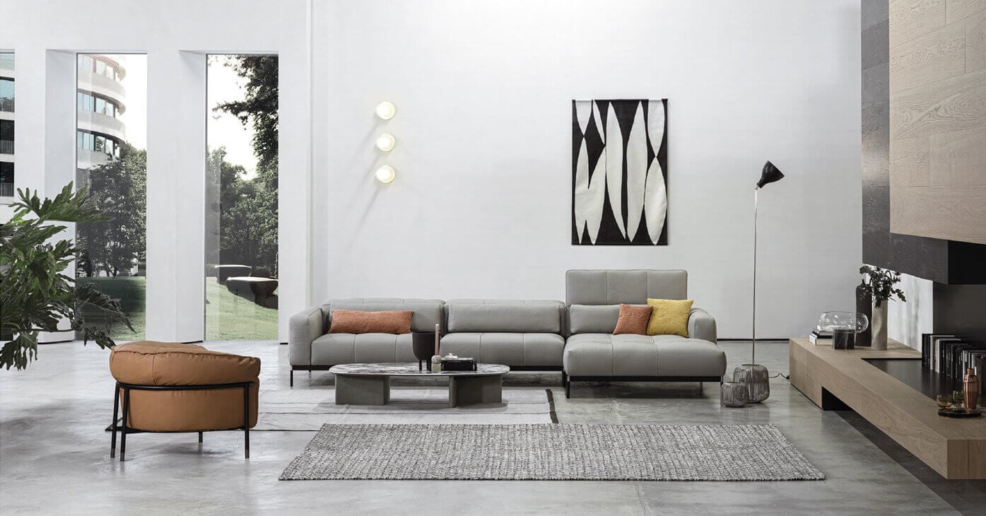 Gray Cierre 1972 "Oscar" sectional sofa with chaise, terracotta & mustard pillows, centered on gray rug with marble coffee table.