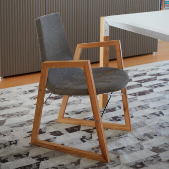 Distinguished Horm Ray armchair with textured matte gray fabric and chrome-plated steel cross-bars built with a light brown wood frame