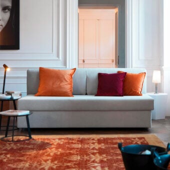 Exceptional Horm Vulcano sofabed with light gray textile upholstery and smooth finish, including orange and burgundy cushions