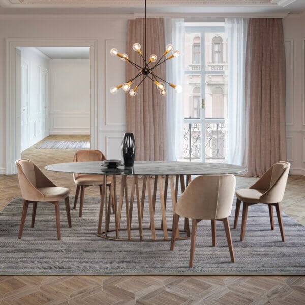 Dining table with light gray marble top and six dark brown upholstered chairs, beneath sputnik chandelier, blush curtains, balcony view.