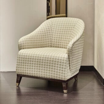 Refined Turri Jolly lounge chair upholstered in beige and light gray houndstooth textile with a dark-toned wood base and metallic end caps