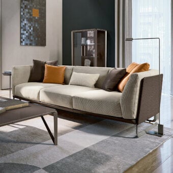 Lavish Turri Milano sofa with woven dark brown leather frame and plush cream textile seating accented with orange