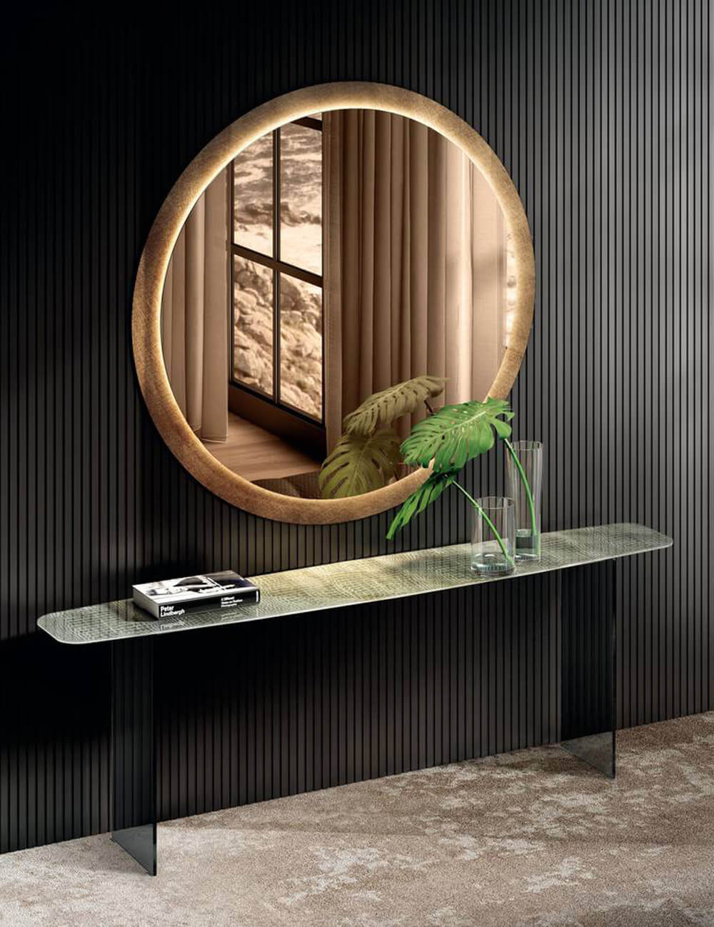 Kibi console table with glass top and black metal frame, paired with round mirror, books, vase, and gray ridged wall paneling.