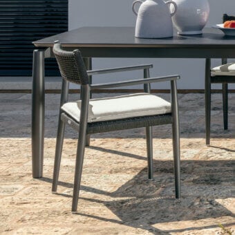 Distinguished Talenti Dolcevita Alu armchair with a matte metal frame and light-colored seat against a dark gray woven backrest
