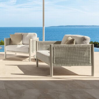 Distinguished Talenti Dolcevita Alu lounge chair with light metal frame and woven synthetic sides cradling light cream cushions