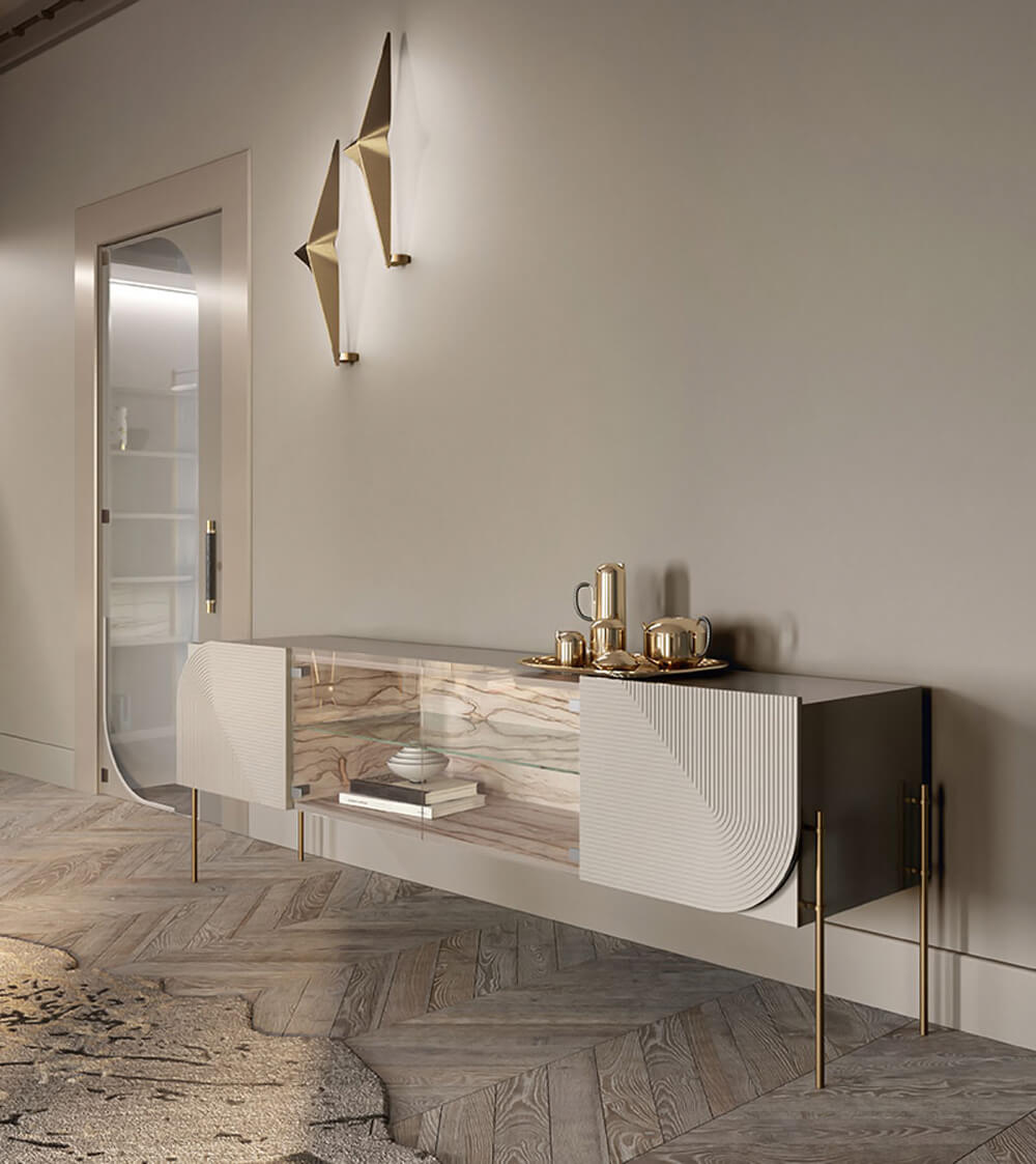 Drop sideboard, dark gray ribbed wood, gold tapered legs, marble-look interior, displayed in room with herringbone floor and gold feather wall art.