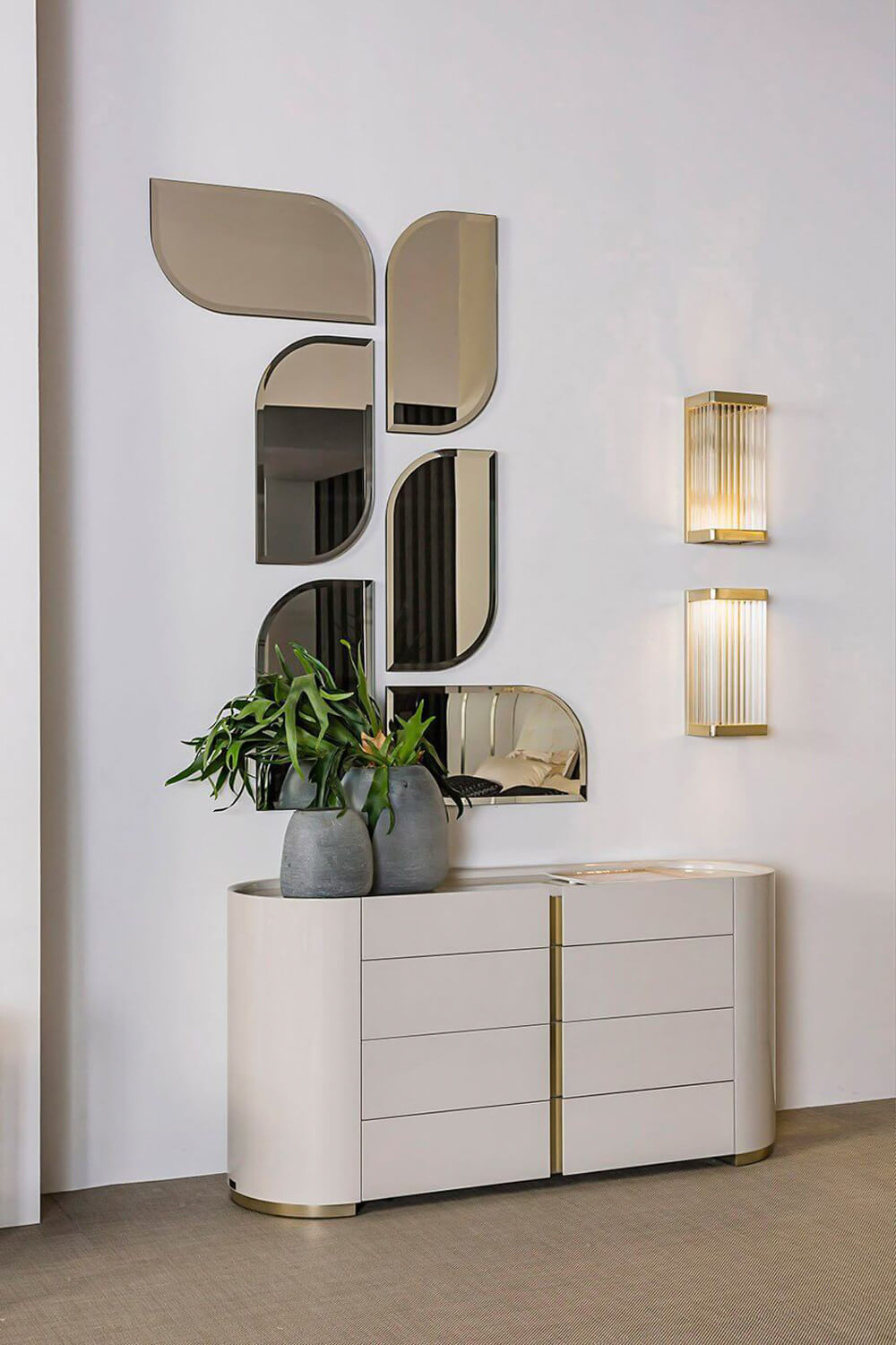 Bizzotto dresser, cream and gold, curved six-drawer design, with bronze mirrors, gold sconces, and green plants in a modern interior.