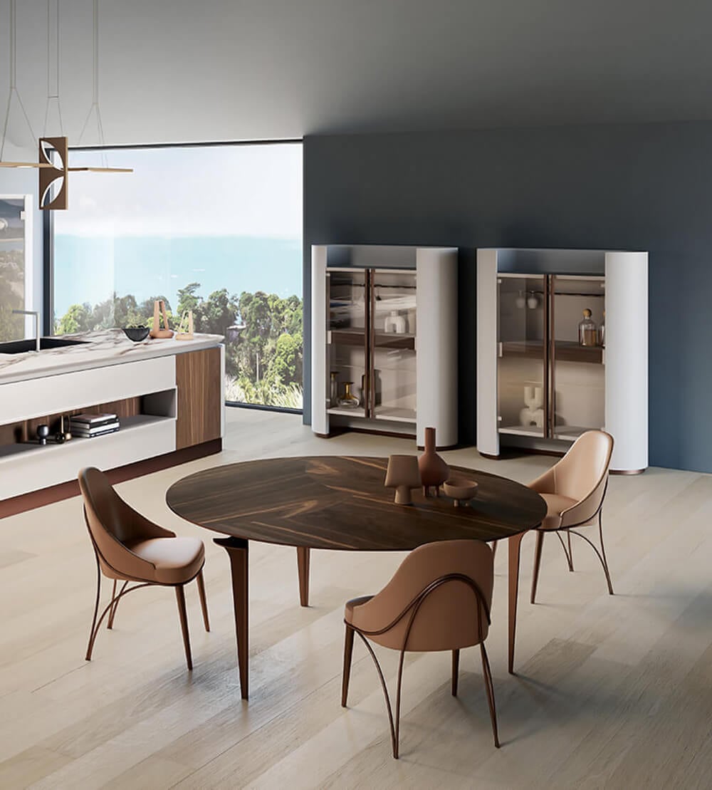 Round dining table with dark brown wood top and light wood legs, surrounded by four light brown leather chairs, in a gray-blue dining room.