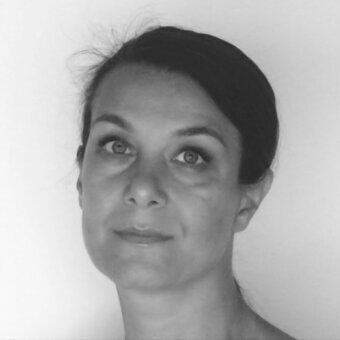 Black and white portrait of Althea Prati with dark hair in a bun, facing upwards with a thoughtful expression, studio lighting.