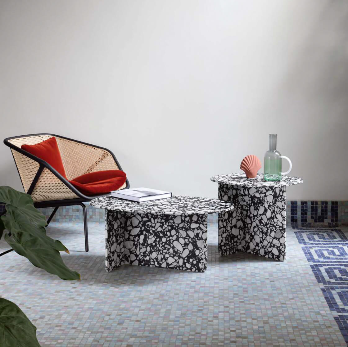 Miniforms Chap coffee tables, terrazzo tops, black trapezoid bases, mosaic tile floor, chair with orange cushion, studio lighting.