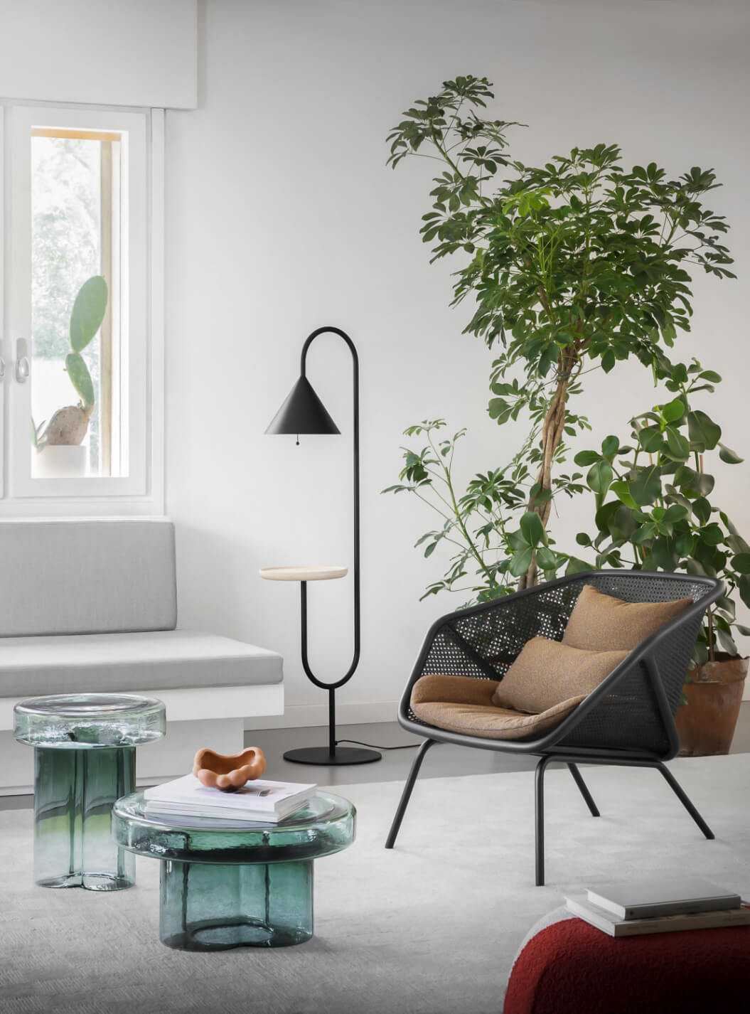 Colony lounge chair by Miniforms with black woven frame, tan cushion, paired with green resin side tables and black conical floor lamp.