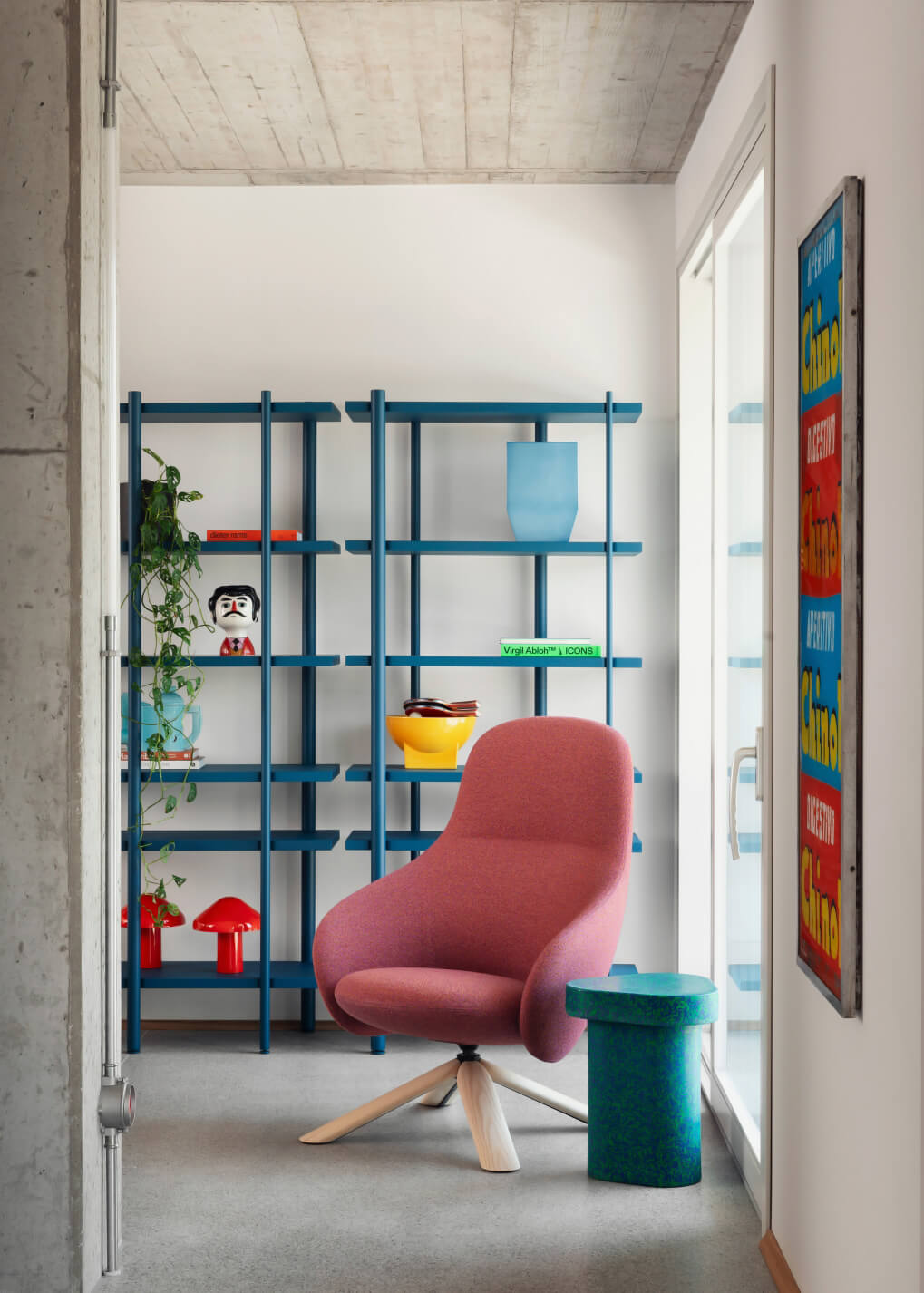 Miniforms Nebula lounge chair, dusty rose fabric, rounded back with teal side table, blue shelving, concrete pillar, modern interior.