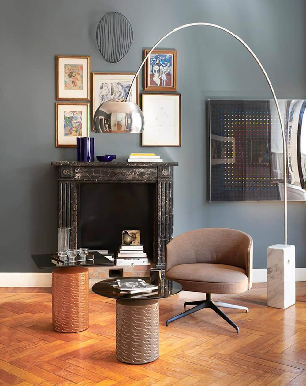 Potocco Hishi side table, bronze geometric base, glass top, with black coffee table, tan armchair, marble fireplace, and arched floor lamp.