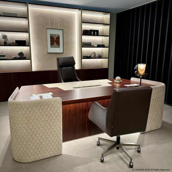Cassoni Mariani executive desk, reddish-brown wood veneer, beige quilted leather panel, silver metal drawer pulls, gray leather chair, wood-paneled office.