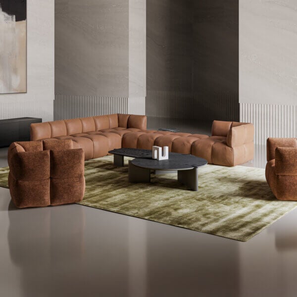 Leather sofa, tan color, quilted texture in a modern living room with stone columns, olive rug, and gray coffee table.