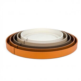 Pinetti Venere trays, tan leather, nested circular design with off-white matte centers and visible stitching, studio product shot.