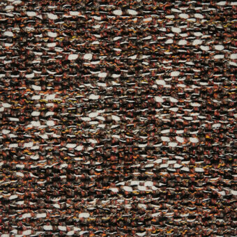 Textile tweed pattern, black, brown, and cream with yellow and orange flecks, featuring a nubby, irregular weave and abstract pebble-like motifs.