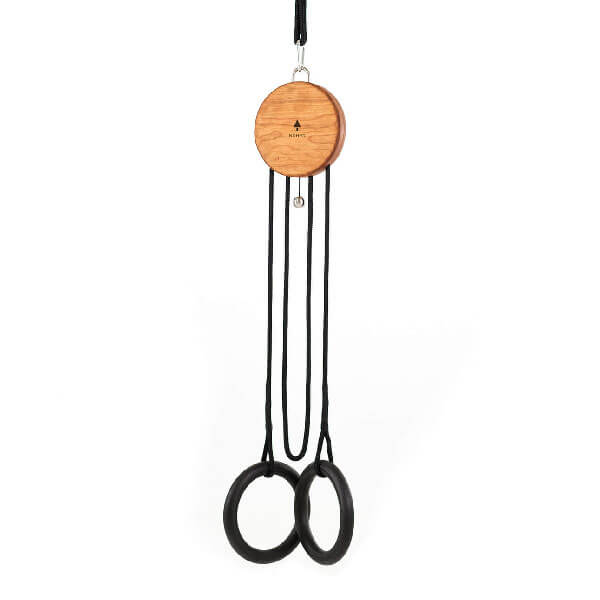 Suspension trainer with circular wood disc, black ropes, and gymnastic rings against a white backdrop, showcasing a minimalist fitness apparatus.