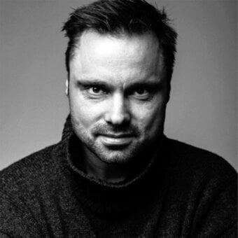Black and white portrait of Matti Klenell, a man with dark hair and beard wearing a gray turtleneck sweater, neutral expression.