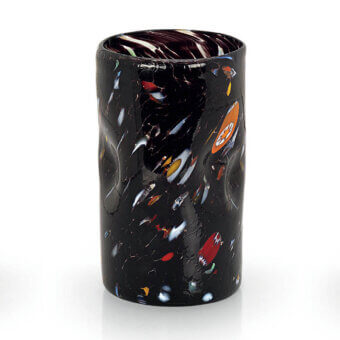 Spotted black glass vessel with irregular red, orange, yellow, blue & white spots, textured surface, purple & white rim, studio shot.