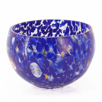 Blue glass bowl with spotted pattern, rounded shape, and glossy finish displayed on a white background in studio lighting.