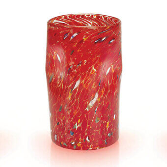 Red glass vase with spotted pattern, cylindrical shape, and swirling gold accents, displayed in a bright studio setting.