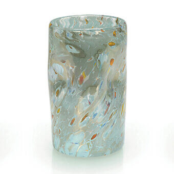 Glass vessel, turquoise with gray and amber spots, cylindrical shape with thick, swirled rim and hand-blown texture on white background.