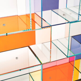 Modular shelving unit, acrylic and glass, geometric arrangement of intersecting planes in orange, white, purple, and blue tones.