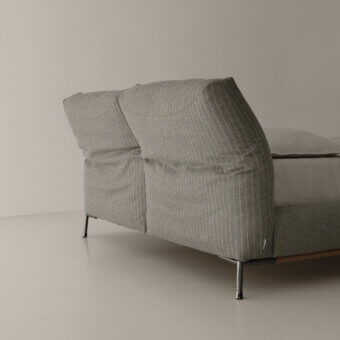 Chapeau bed, gray striped fabric, padded headboard with silver metal frame and cylindrical legs, studio shot.