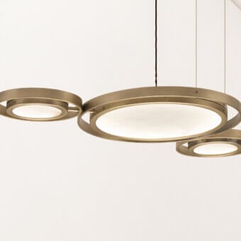 Cassoni Girasole suspension lamp, brushed brass, three overlapping circular rings with warm white illuminated panels, modern design.
