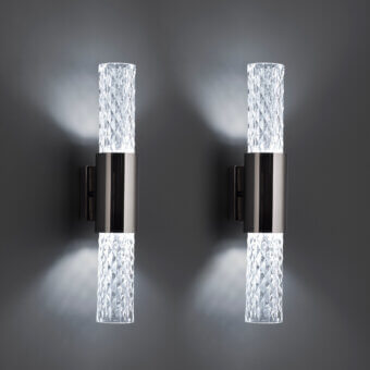 Wall lamps, clear glass facets, dark gray metal housing, cylindrical shape, geometric design, mounted on gray wall, emitting white light.