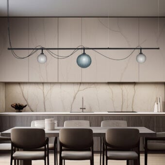 Le Perle suspension lamp with dark metal bar and four spherical glass shades over beige and gray kitchen with marble tile backsplash.