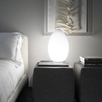Exclusive FontanaArte Uovo table lamp embodying a natural form with white satin blown glass and painted metal base