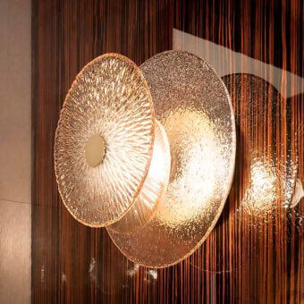 Sicis Andromeda wall lamp, wood veneer, layered textured glass discs, warm gold hardware, modern lighting fixture.