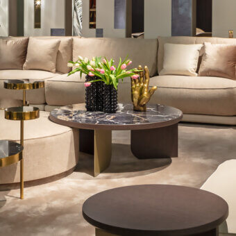 Sicis Liam coffee table, dark marble top with grey veining, geometric dark brown wood base, styled with flowers and sculpture.